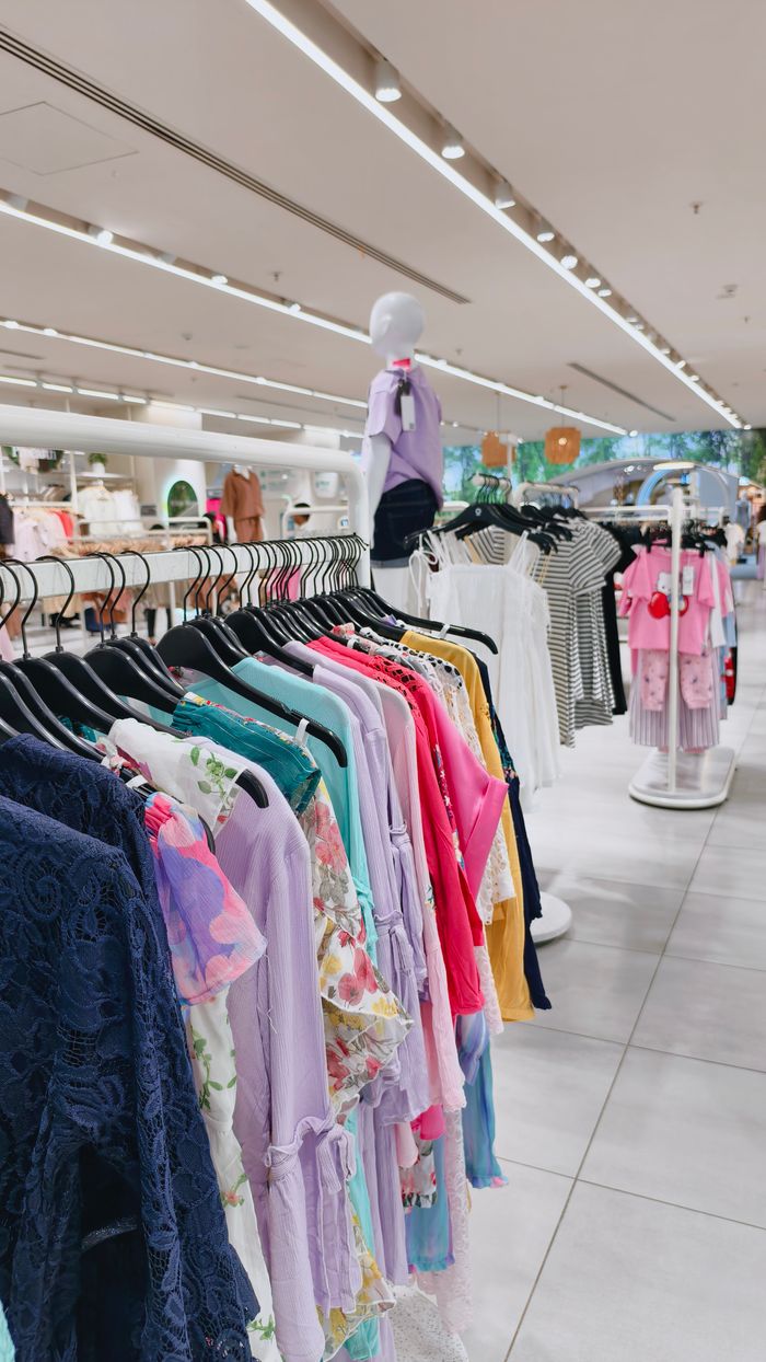 Diverse array of colorful clothes on hangers in a modern retail space with mannequins.